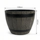 A dark gray faux-wood barrel planter with black metal bands, shown with dimension lines indicating a diameter of 38cm and a height of 27cm on a white background.